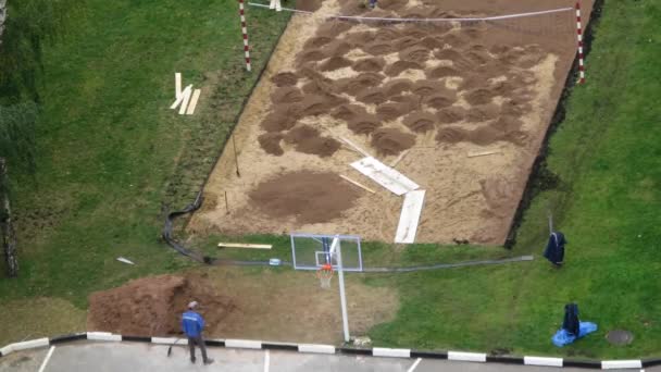 Рабочие приносят и заливают песок на волейбольную площадку — стоковое видео