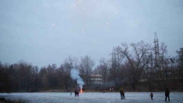 Gente en pista de hielo lanza fuegos artificiales por la noche — Vídeo de stock