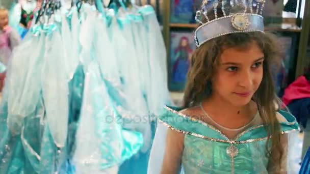 Meisje in de jurk van een prinses en kraaien in de winkel — Stockvideo