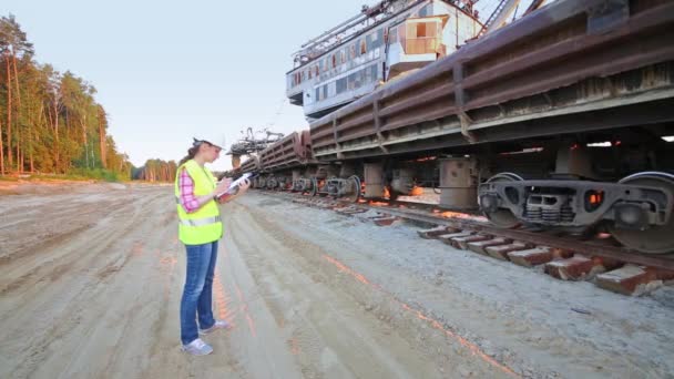 Een vrouwelijke werknemer gesprekken over walky-talky naast de trein — Stockvideo