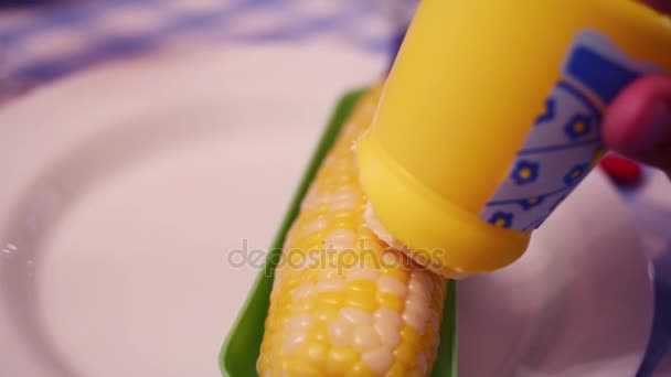 Dziewczyna, namaszczenie masło gotowanej kukurydzy — Wideo stockowe