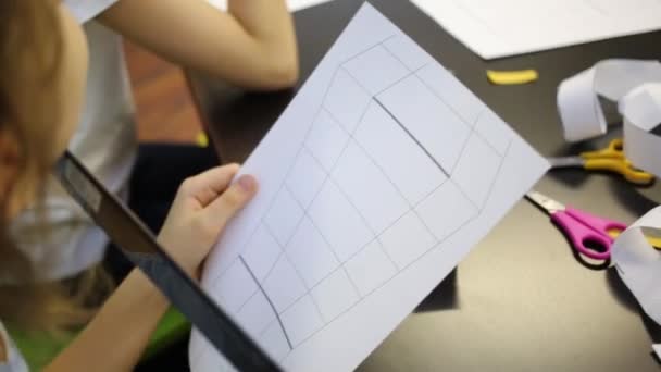 Menina segurando folha alinhada de papel na sala de aula — Vídeo de Stock