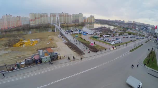 Urban sector with pedestrian bridge over river — Stock Video