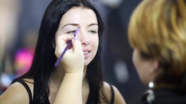 Maquillaje artista pinta la ceja de modelo de niña — Vídeo de stock