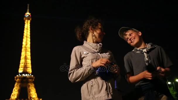 Madre e hijo de pie cerca de la torre Eiffel por la noche — Vídeo de stock