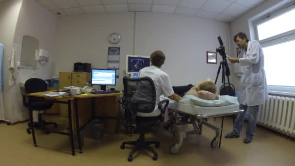 A doctor holds a patient ultrasound, a man photographing it — Stock Video