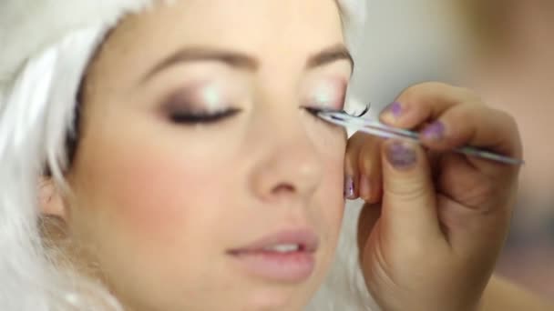 Makeup artist attaches false eyelashes on upper eyelid of model — Stock Video