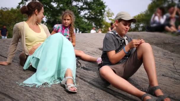 Mutter mit Kindern sitzt und ruht auf Felsen — Stockvideo