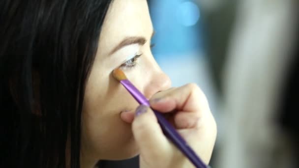 Visagiste applies makeup using brush on the lower eyelid of model — Stock Video