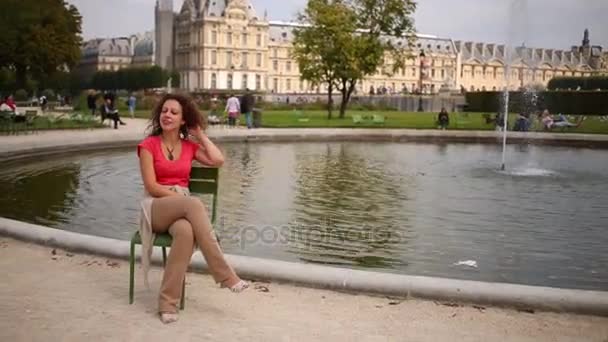 Menschen ruhen sich rund um Teich mit Brunnen im Garten der Tuilerien aus — Stockvideo