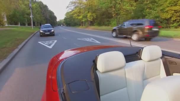 Κυκλοφορία των αυτοκινήτων στο δρόμο πίσω από το κόκκινο καμπριολέ — Αρχείο Βίντεο