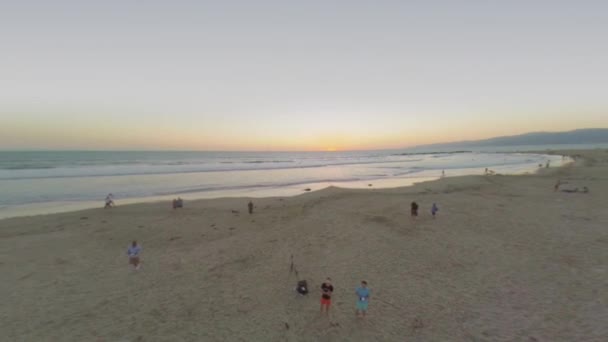 Menschen am Strand bei Sonnenuntergang — Stockvideo