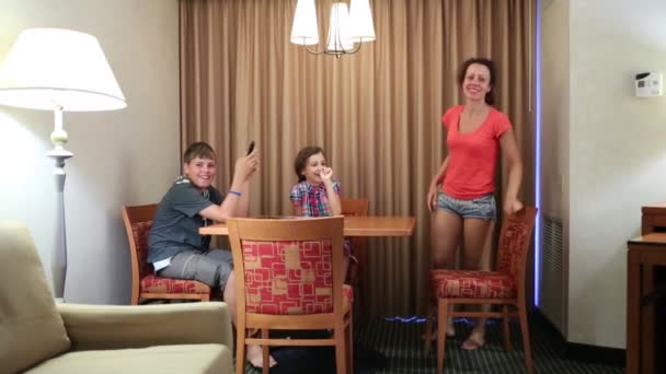 Женщина с детьми сидит за столом в комнате — стоковое видео