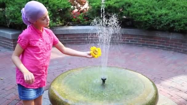 Kız çiçek ve çeşme ile çalış ve çocuk o görünüyor — Stok video