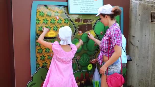 Женщина с детьми находит животных на интерактивной карте — стоковое видео