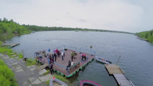La gente en el muelle en el lago en día nublado — Vídeo de stock
