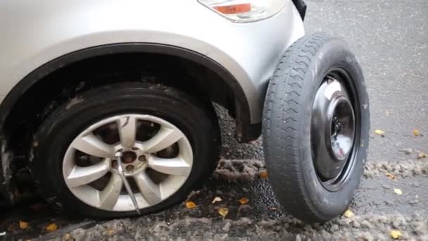 Lekke band van moderne auto, jack en reservewiel een asfalt — Stockvideo