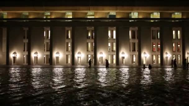 Waves on pond near building and silhouettes of people — Stock Video