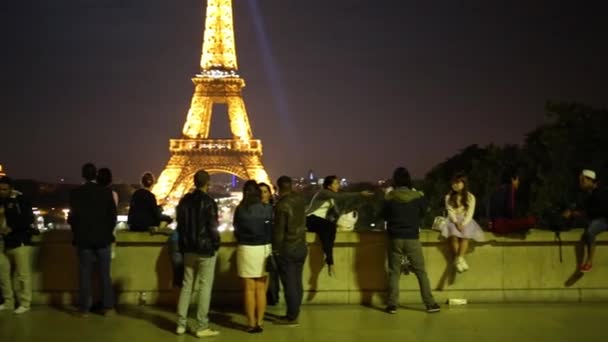 Los turistas miran la Torre Eiffel por la noche — Vídeos de Stock