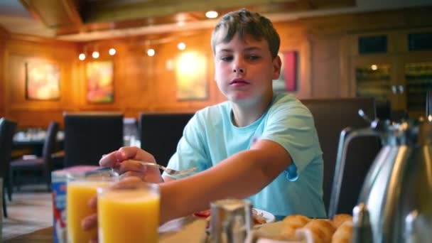 Menino café da manhã e bebidas suco no café — Vídeo de Stock