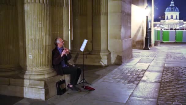 Musician sits on the bottom of column and plays the flute — Stock Video