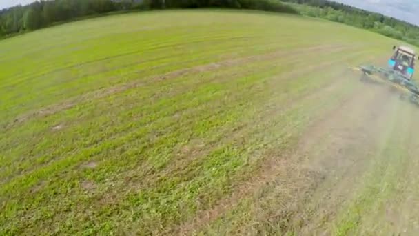 Grass field with tractor which collects hay — Stock Video