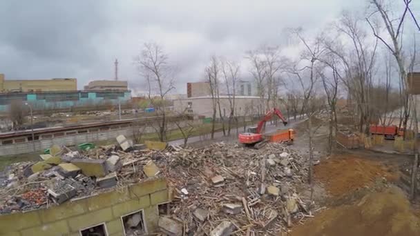 Ruiner av gamla byggnad och grävmaskin laster lastbil — Stockvideo