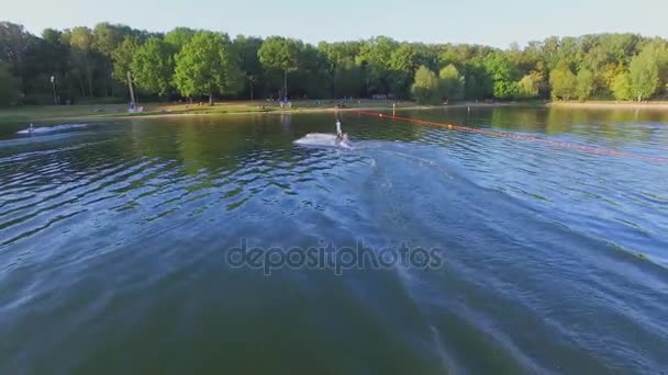 Человек едет на вейкборде по поверхности воды — стоковое видео