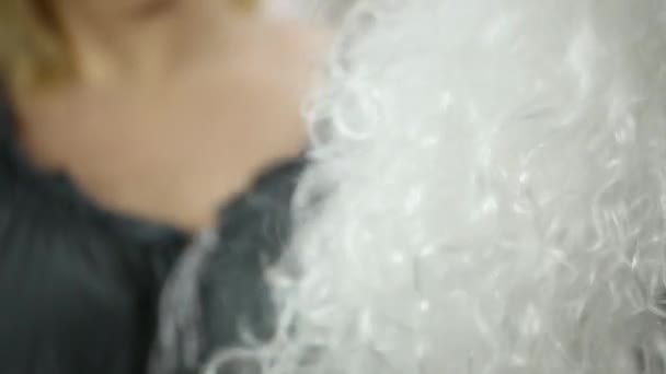 Висагисте расчесывает белый искусственный кудрявый парик — стоковое видео