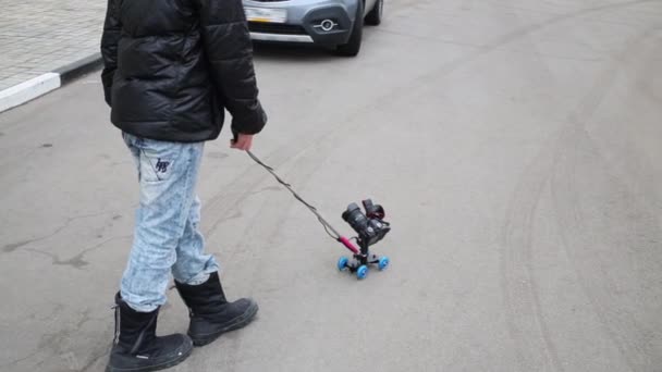 Garçon avec caméra sur rouleau sur asphalte près des voitures — Video