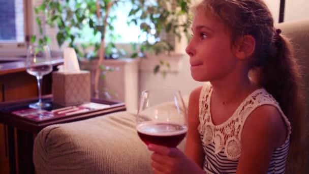 Девушка сидит на диване и пьет вино — стоковое видео