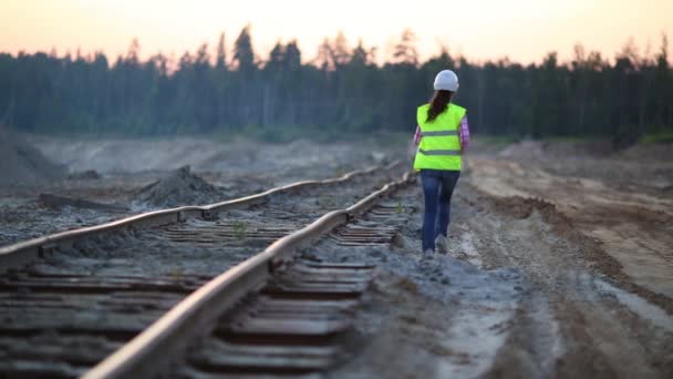 Женщина-работница в отражающей куртке бежит возле железной дороги — стоковое видео