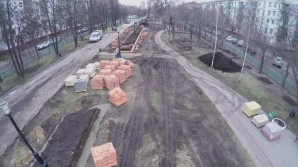 Люди строят клумбы из кирпича на бульваре — стоковое видео