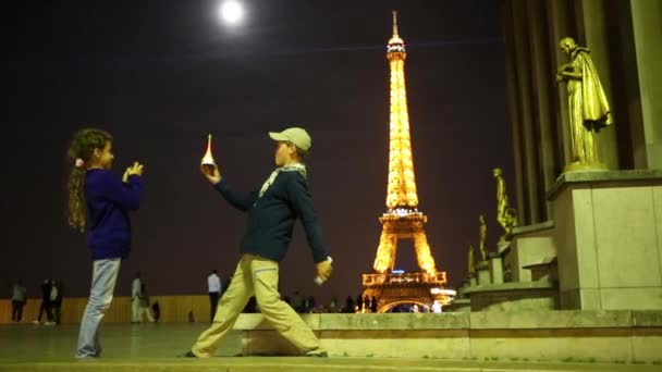 Chico y chica se divierten cerca de esculturas y torre Eiffel — Vídeo de stock