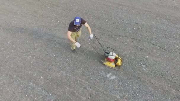 Man crushing gravel by special machine on road — Stock Video