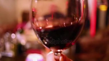 El şarap şeffaf bir bardağı sallıyor.
