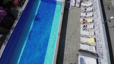 insanlar havuzu yakınındaki şezlong üzerinde dinleniyor