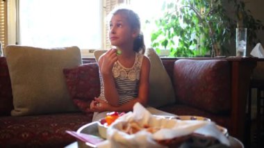 Kız koltukta oturur ve salatalık yiyor 