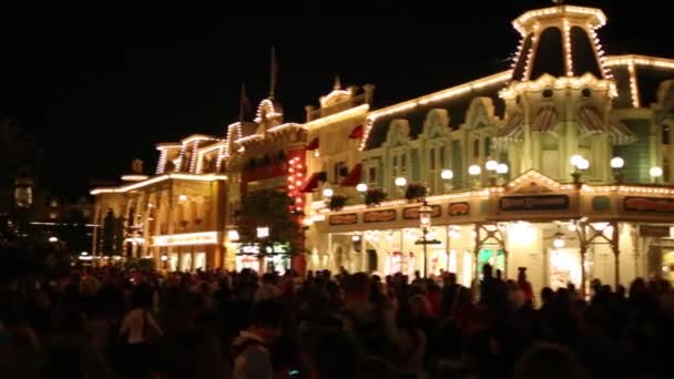 As pessoas caminham rua abaixo à noite na Disneylândia — Vídeo de Stock