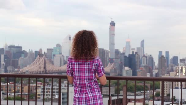 Kvinnan står på taket och tittar på Queensboro bridge — Stockvideo