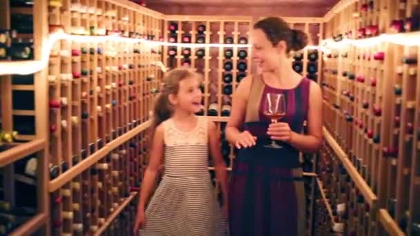 Niña y su madre de pie entre los estantes con vino — Vídeo de stock