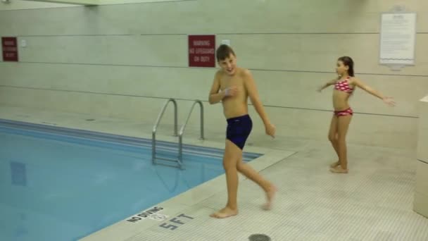Chico salta a la piscina cubierta — Vídeo de stock
