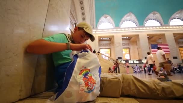 Boy sits on floor in Grand Central Station — Stock Video