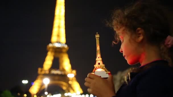 Girl holds illuminated miniature near Eiffel tower — Stock Video