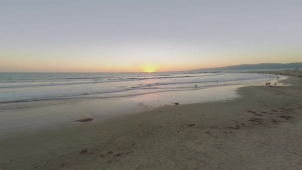 Personas en la playa durante el atardecer — Vídeo de stock