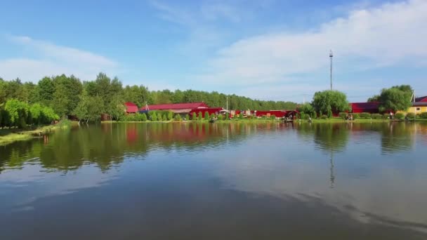 Lake with reflection of fish farm buildings on shore — Stock Video