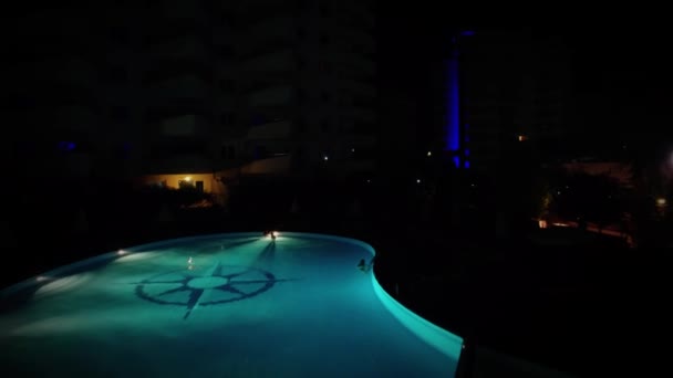 Illuminated pool with people near edifice of residential complex — Stock Video