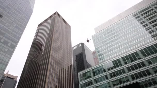 Man afstandsbedieningen quadrocopter onder glas wolkenkrabbers — Stockvideo