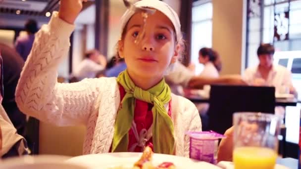 Chica sonríe y come comida en el restaurante — Vídeo de stock