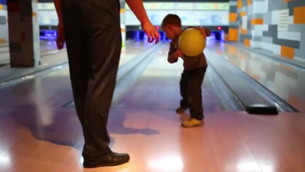 Мальчик учится бросать мяч в боулинг — стоковое видео